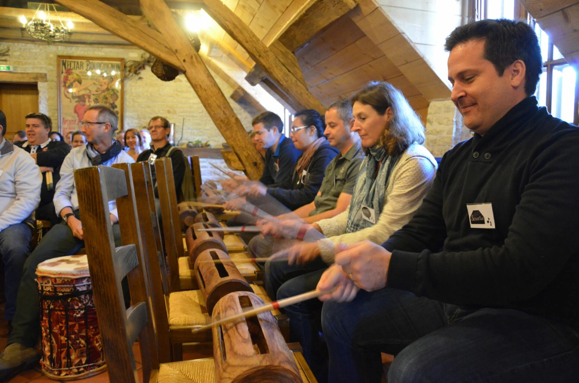 Des participants d’un séminaire d’entreprise jouent ensemble sur des instruments de percussion en bois lors d’une activité de team building.