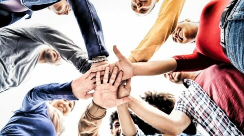 Happy multiracial young people team stacking hands together