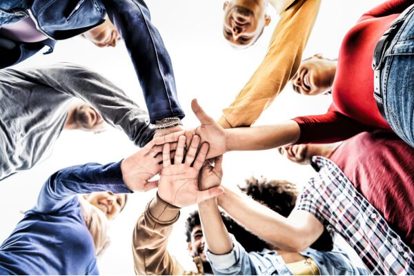 Happy multiracial young people team stacking hands together